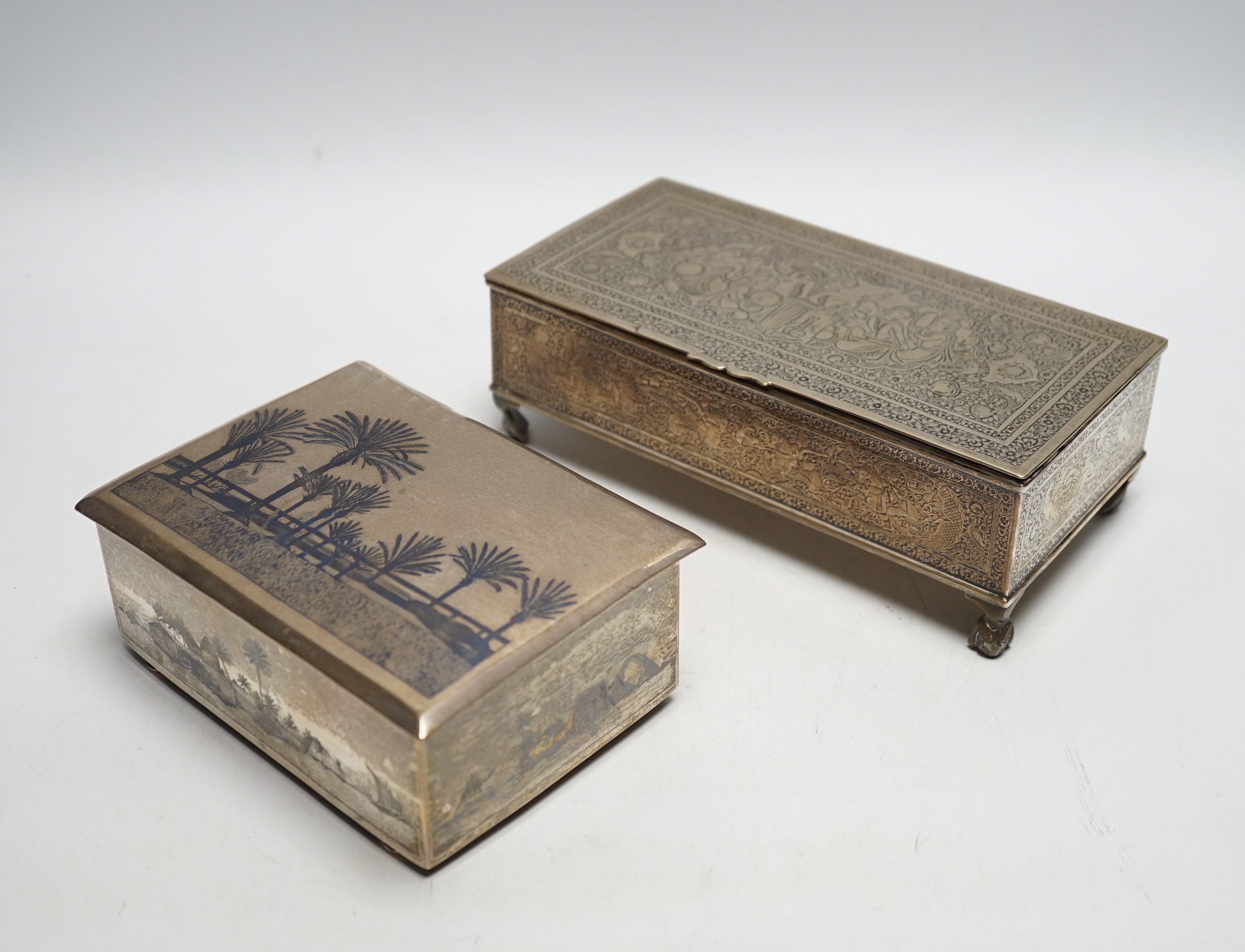 A Persian engraved white metal rectangular cigarette box and a similar white metal and niello cigarette box, largest 20.3cm.